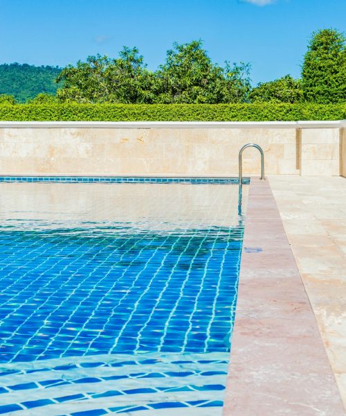 Bright and tranquil poolside scene, capturing a turquoise swimming pool under a clear blue sky.