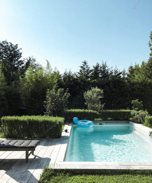 Quiet backyard pool surrounded by greenery and blue skies, ideal for relaxation.